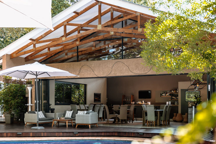 Open-air lounge, bar and poolside seating under the timber roof at Sandalwood Lodge